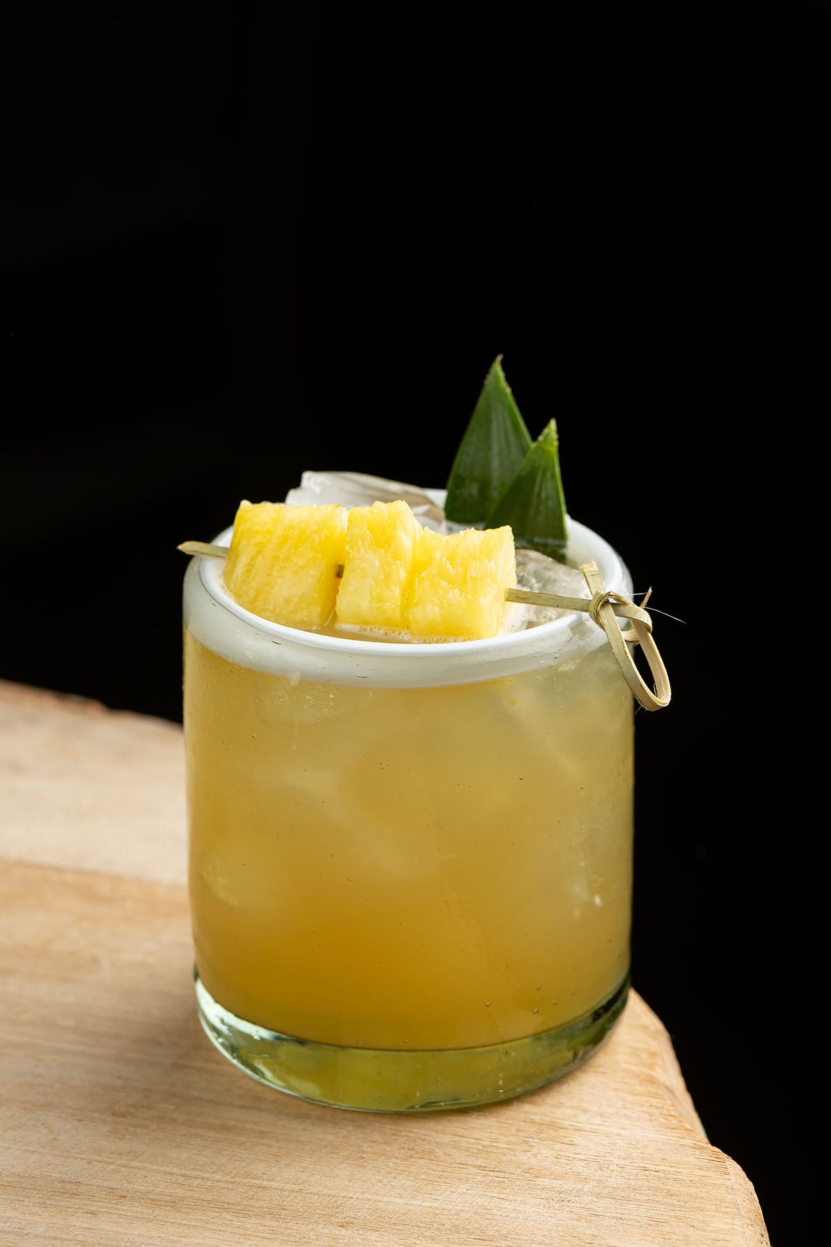 A yellow pineapple cocktail in a short glass.
