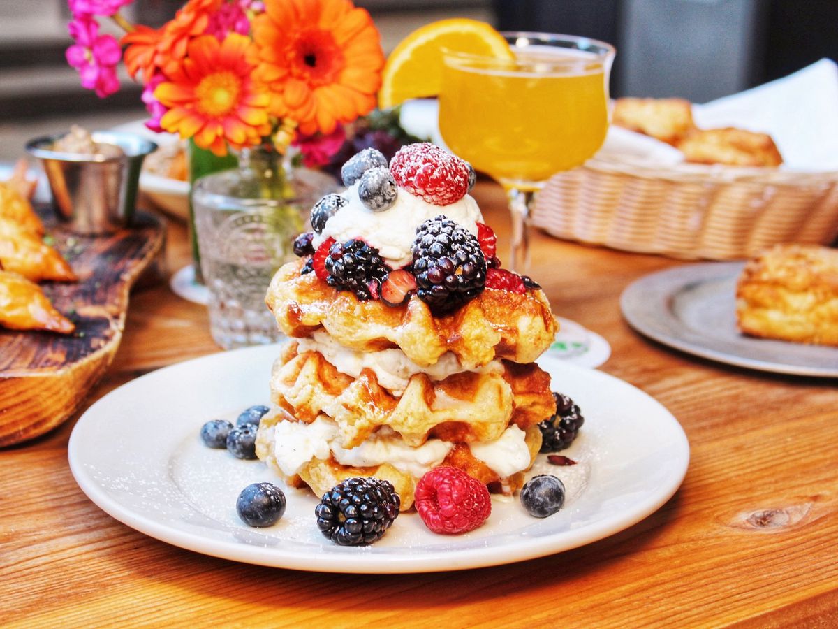 A plate of stacked waffles with creams and berries.
