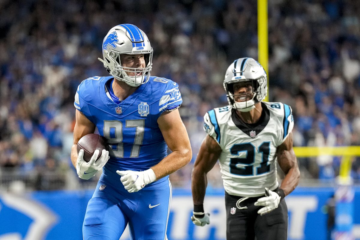 Sam LaPorta #87 of the Detroit Lions runs with the ball while being chased by Jeremy Chinn #21 of the Carolina Panthers in the second quarter at Ford Field on October 08, 2023 in Detroit, Michigan.
