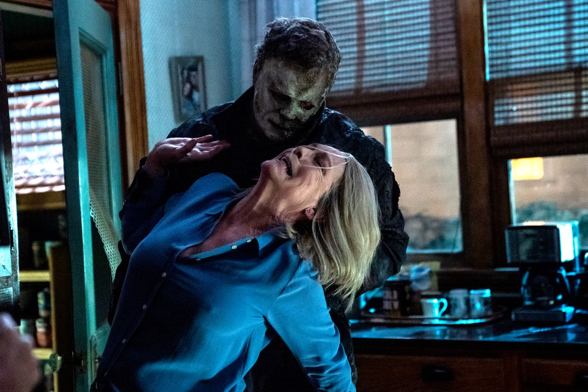 Bathed in blue light, Michael Myers twists Laurie’s arm in the kitchen in Halloween Ends