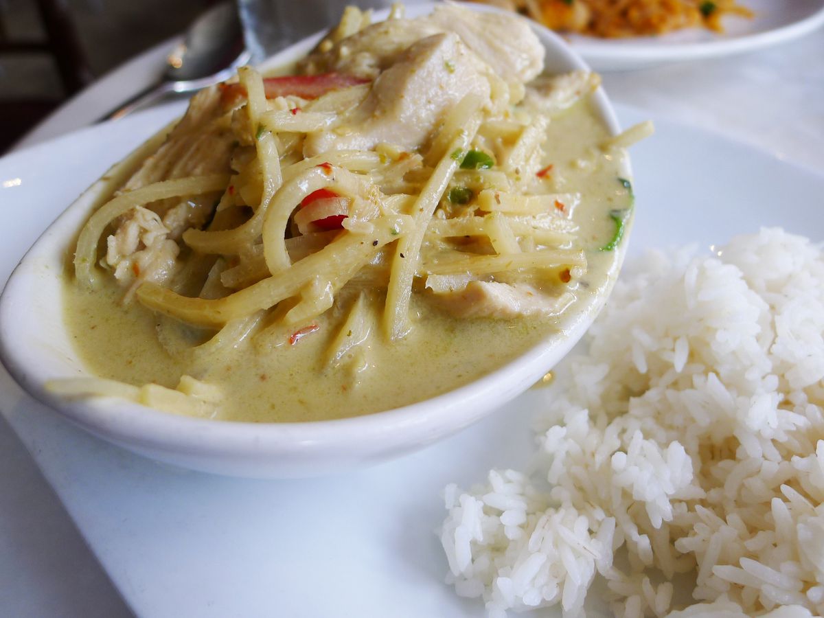 A bowl of chicken curry with a pale green broth.