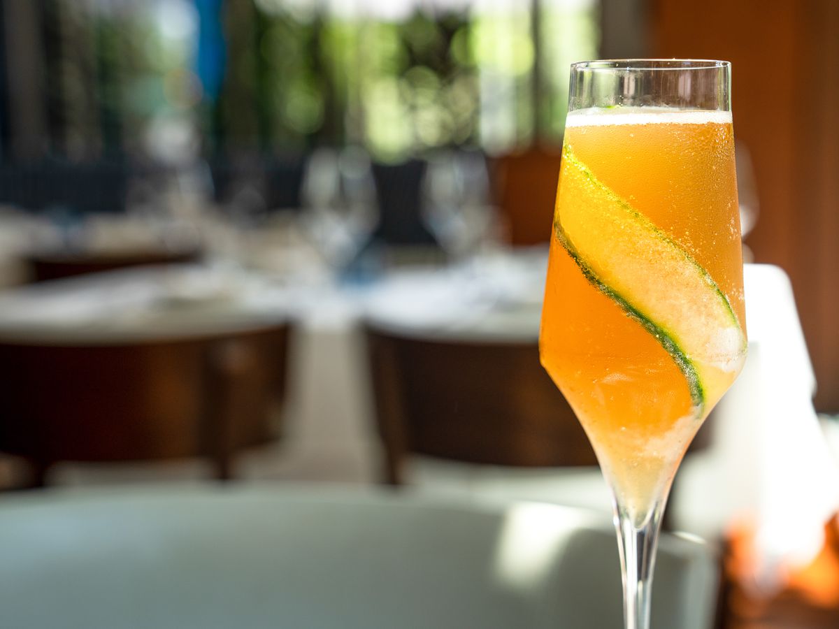 An orange-hued drink in a champagne flute
