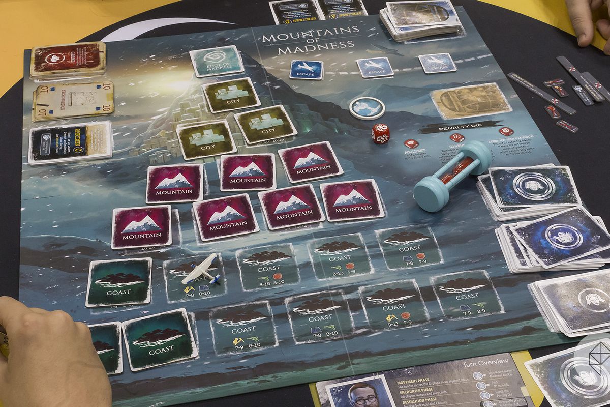 A pyramid of cards sits face down on the game board representing the mountain itself. A sand timer sits to one side.