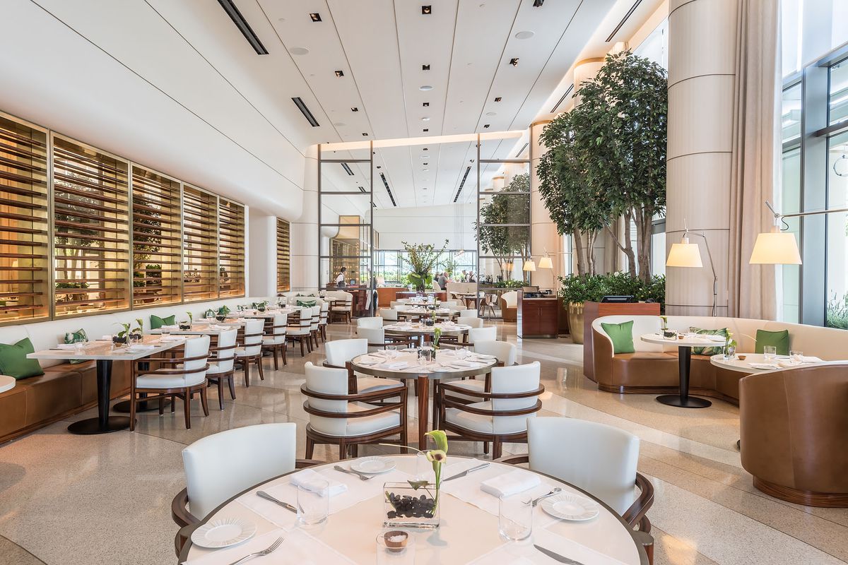 A bright look down the center of a sunny daytime restaurant with dark wood seats at a high-end hotel.