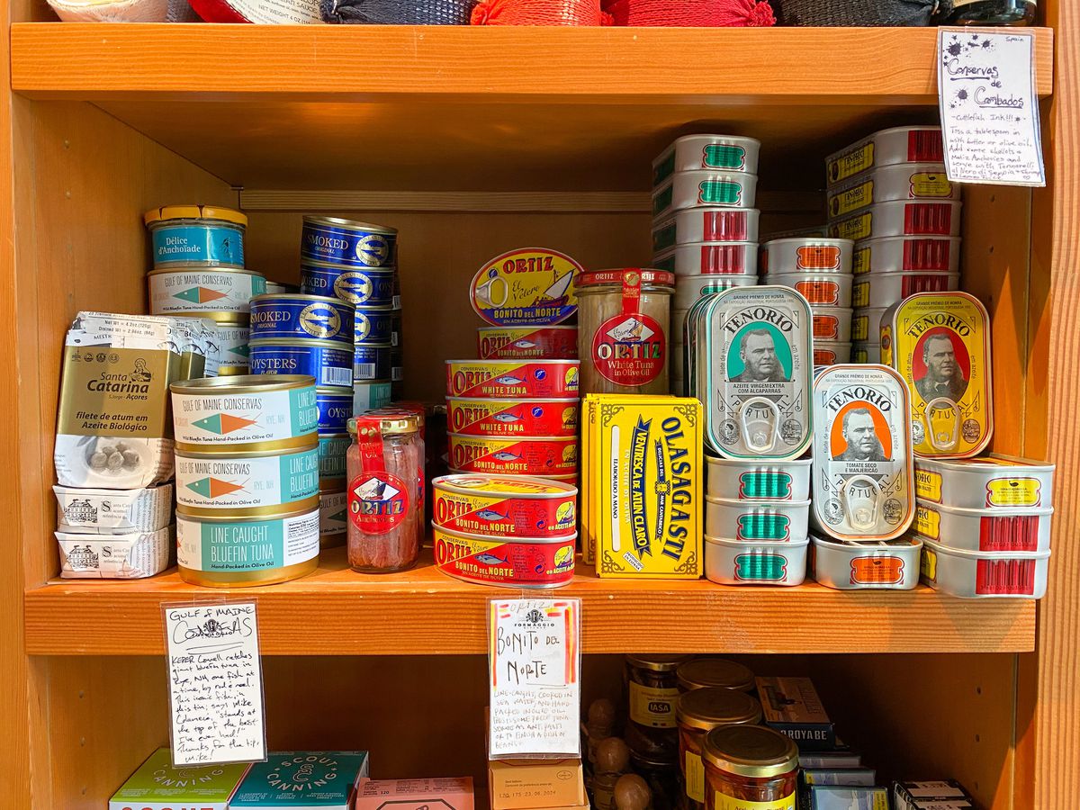 A wooden shelf filled with a variety of tinned fish.