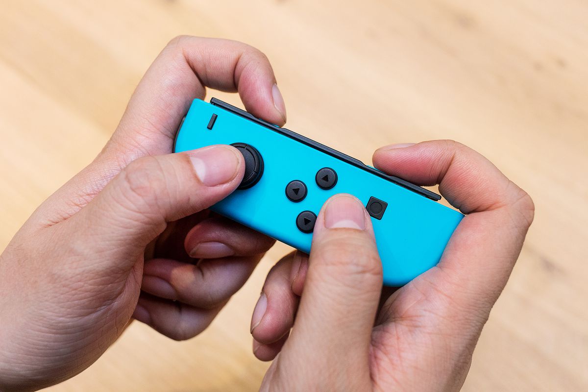 A blue Nintendo Switch Joy-Con being held sideways in someone’s hand 