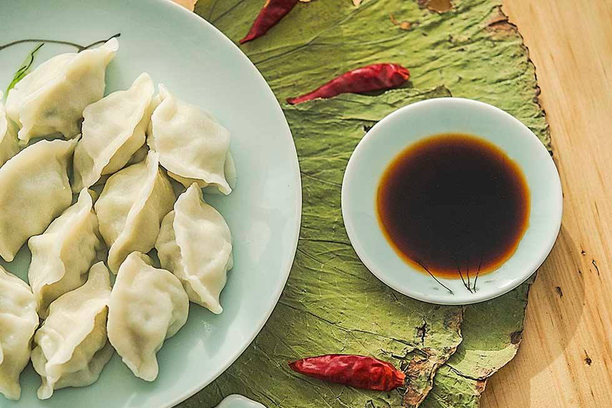 A plate of Chinese dumplings and a dish of dipping sauce.