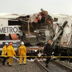 FILE - In this Jan. 26, 2005 file photo emergency workers stand near the wreckage of a train crash, in Glendale, Calif. In response to that 2005 accident that killed 11 people, Southern California's Metrolink commuter railroad bought new passenger cars equipped with "crash energy management" systems. On Tuesday, Feb. 24, 2015 that investment appeared to have paid off when a Metrolink train smashed into an abandoned truck in a crash remarkably similar to the 2005 wreck. 