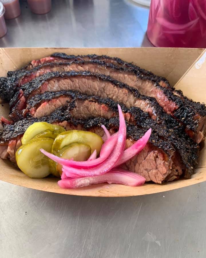 A paper tray of sliced brisket, pickle slices, and onions from Whitfield’s