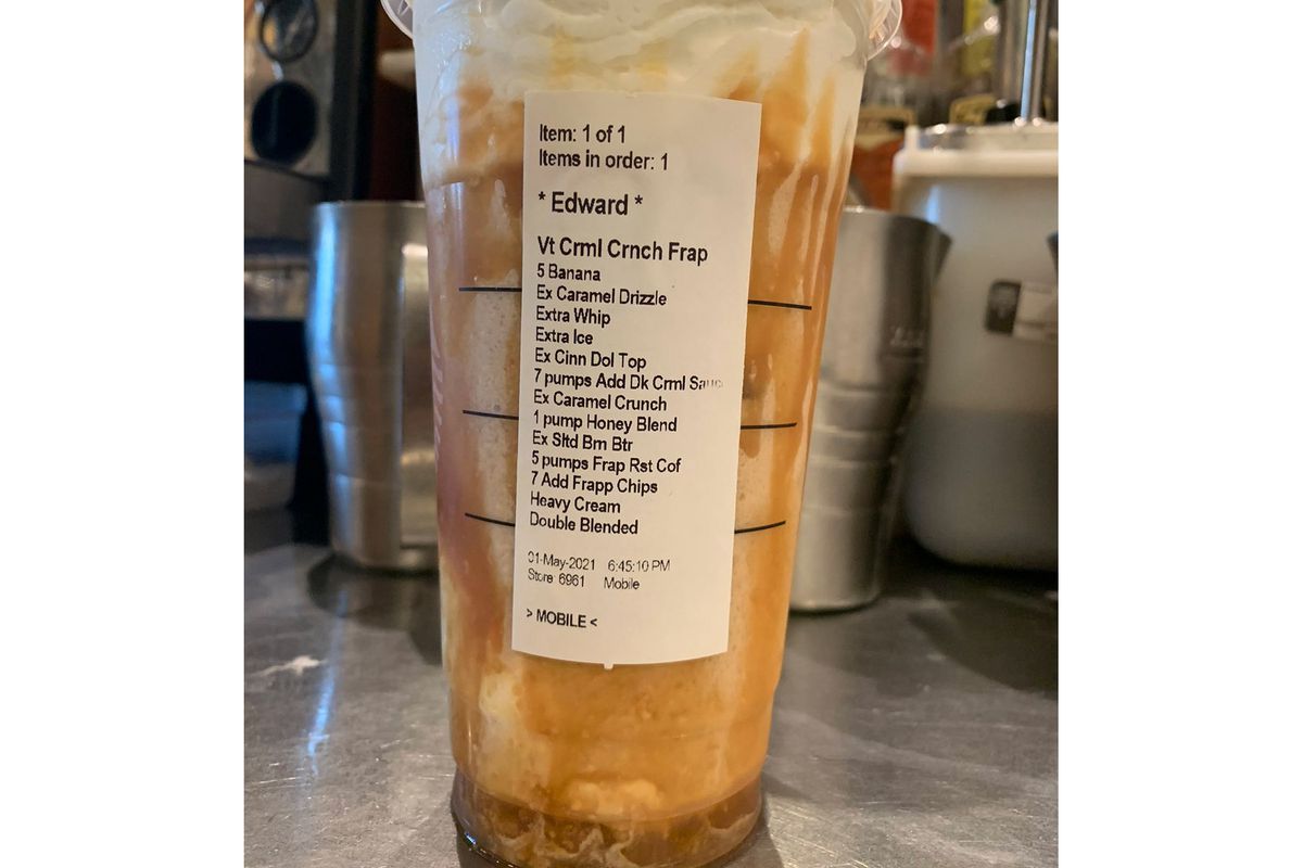 A plastic cup of iced coffee with a long receipt on the front detailing 13 modifications
