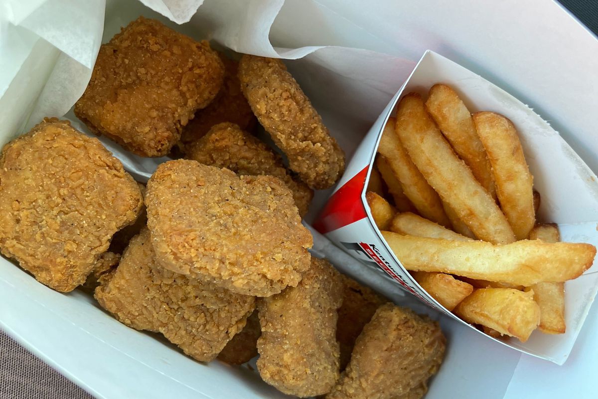 Eight chicken nuggets and a carton of french fries inside a box.