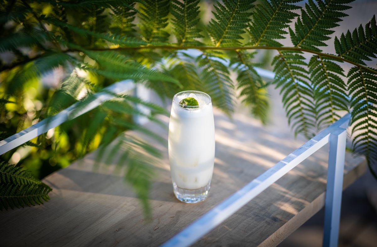 A tall pina colada glass surrounded by leaves.
