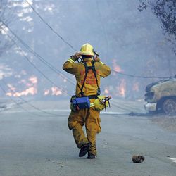 A San Bernardino County firefighter walks down the street towards a fire in Lake Arrowhead, Calif., Monday.