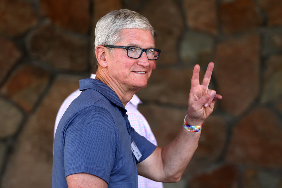 Apple CEO Tim Cook makes a peace sign gesture as he waves to photographers as he enters the Sun Valley Resort.