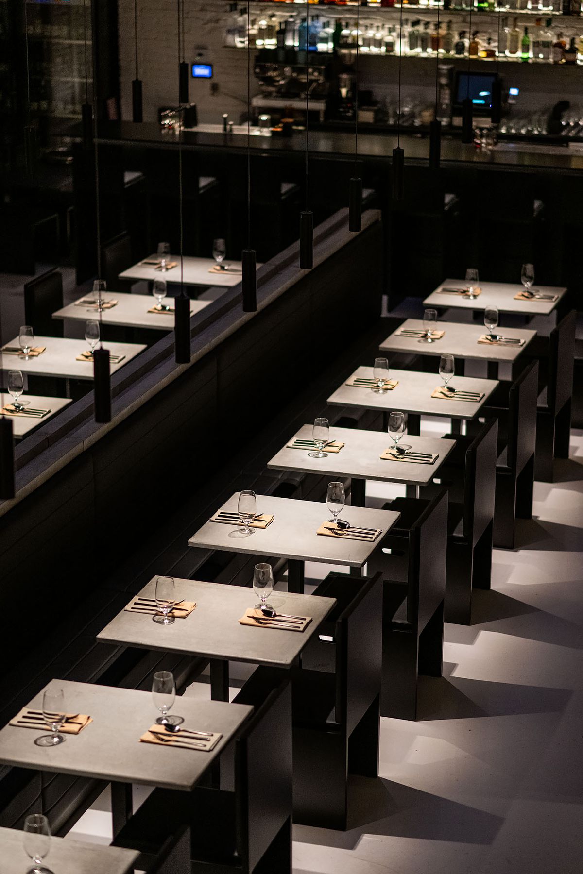 A row of minimalist gray tables set for dinner.