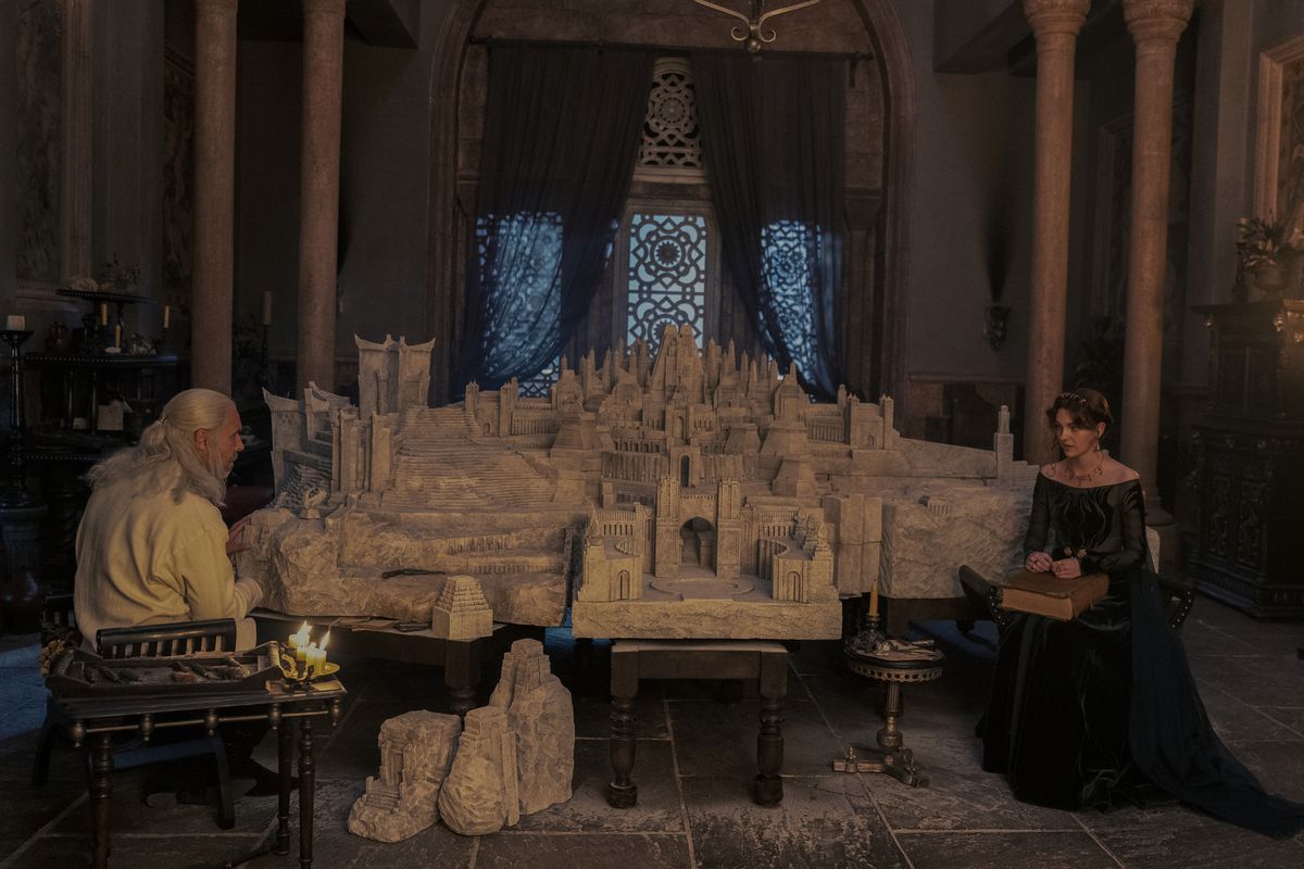 Viserys and Alicent sitting in chairs with a massive model of Old Valyria on the table between them