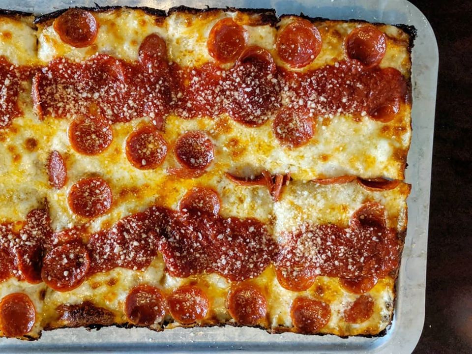 Overhead view of a rectangular pepperoni pizza, with two horizontal strips of tomato sauce across