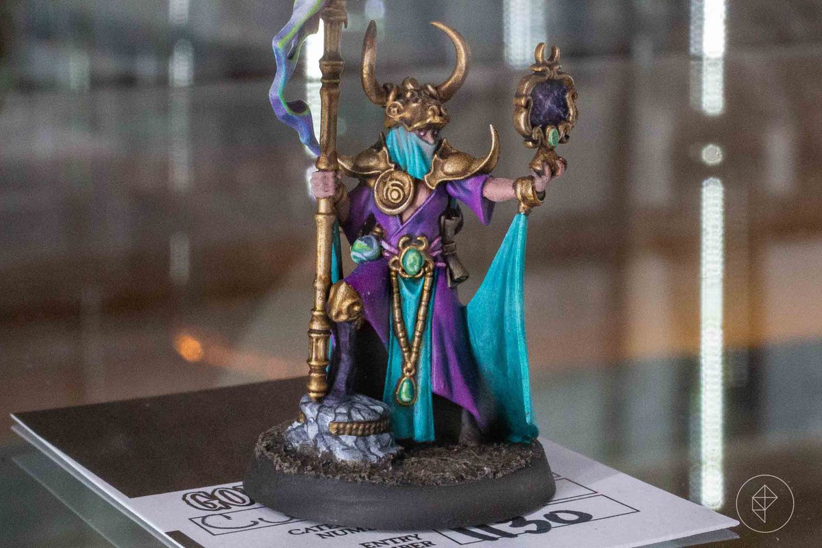 A purple-clad sorceress holds up a magical device.