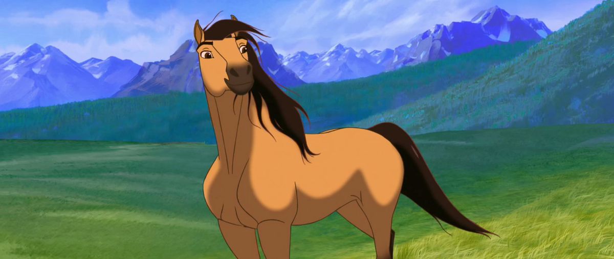 a tan horse standing in a lush green field; he has a dark mane and snout