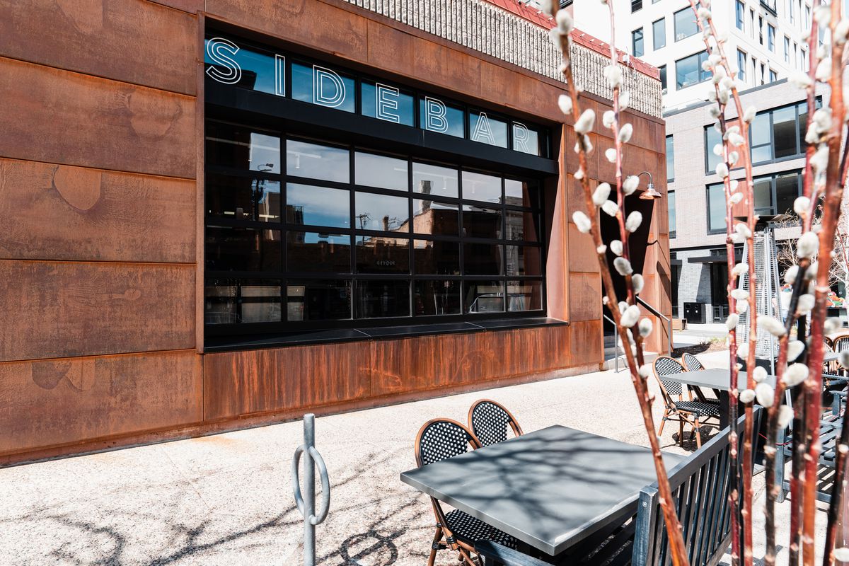 The copper exterior of the restaurant is dominated by a black silloutted garage door front window space that occupies much of the facade. It’s all visible past sidewalk tables decorated with pussy willows.