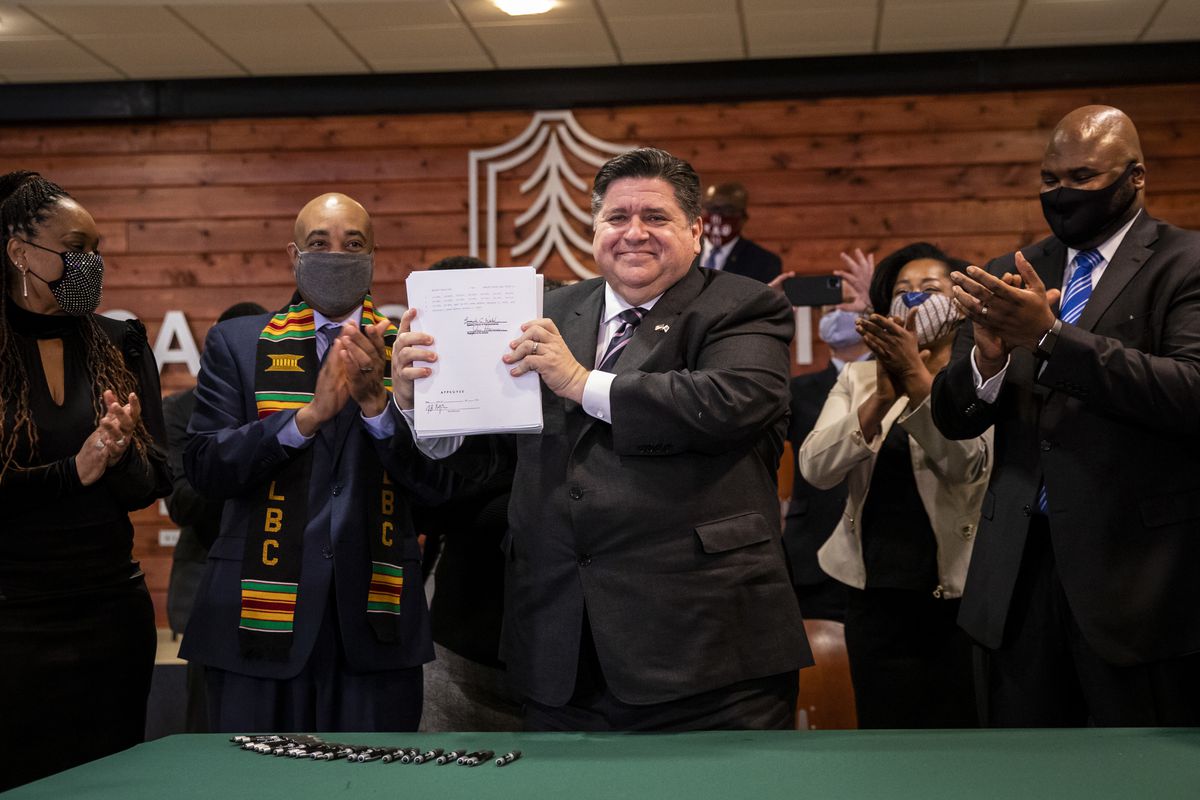Gov. J.B. Pritzker holds up the nearly 800-page signed sweeping criminal justice reform bill Monday at Chicago State University.