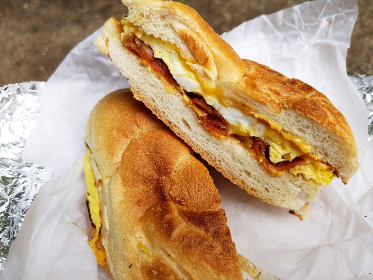 A sandwich shown in cross section on roll containing egg, bacon, and cheese.
