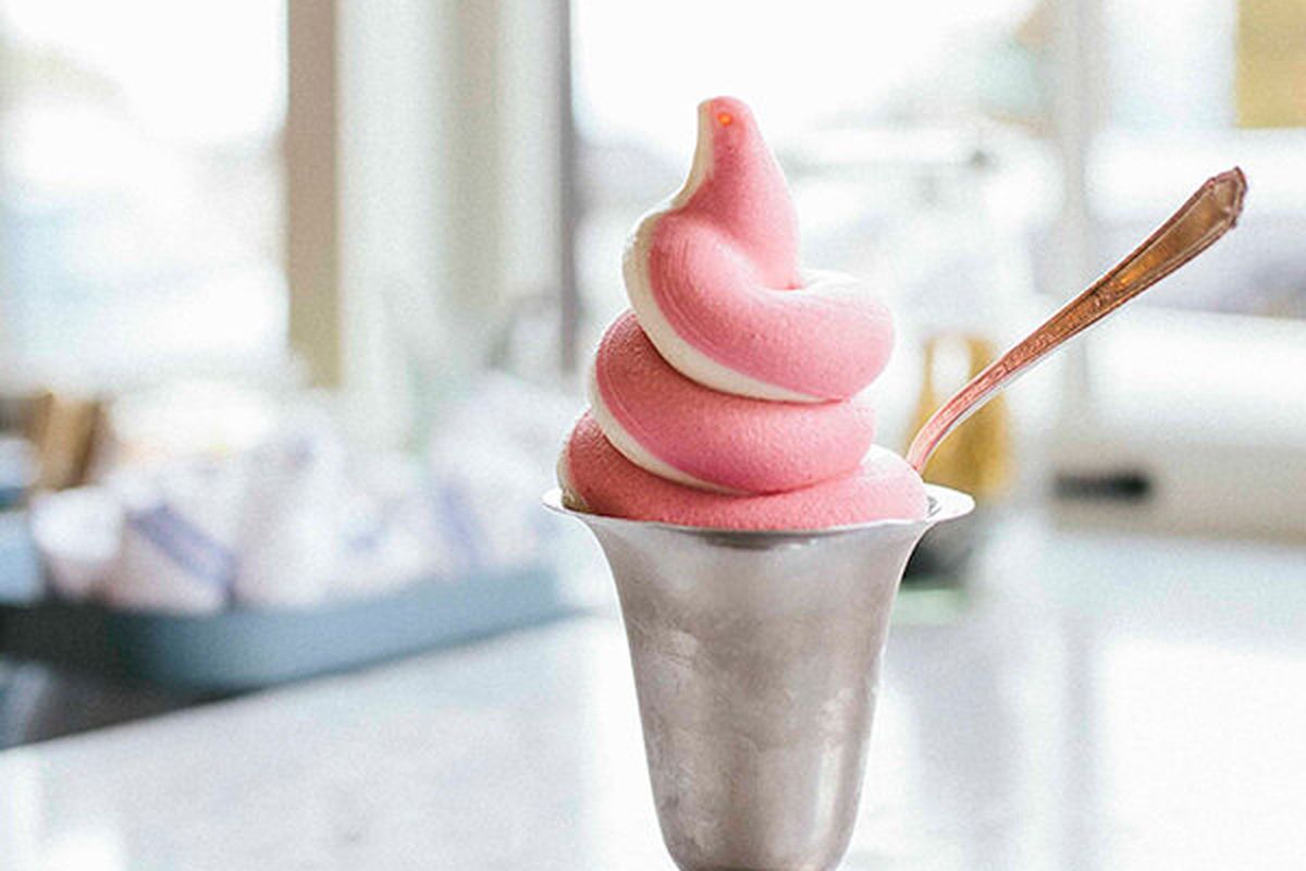 Light pink and white soft serve in a metal ice cream bowl, with a spoon.