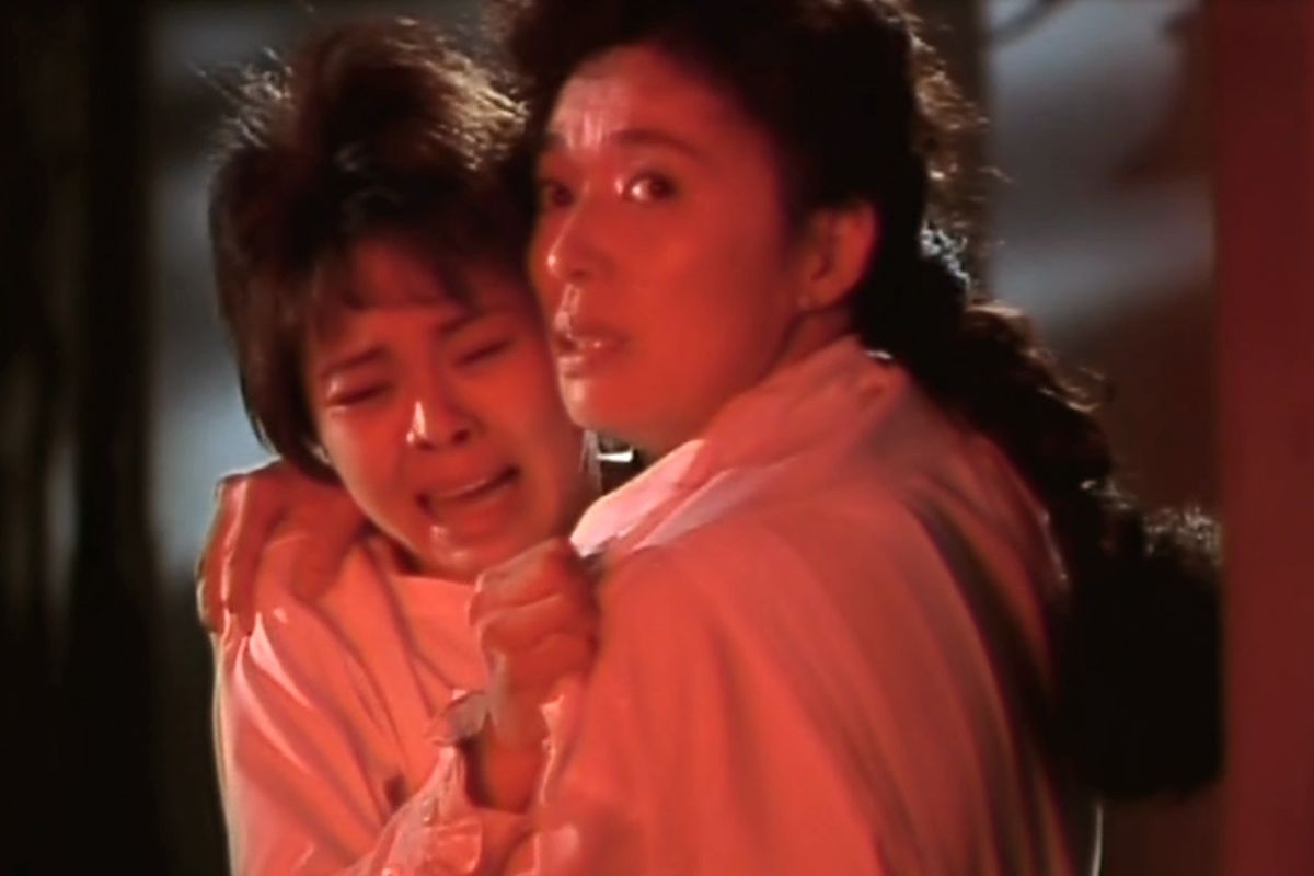 Akiko (Nobuko Miyamoto) holds Emi (Nokko) as they watch Asuka’s melting body in a still from Sweet Home