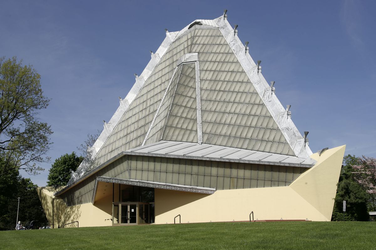 The exterior of Beth Sholom Synagogue. The facade is tan with a glass geometric roof.