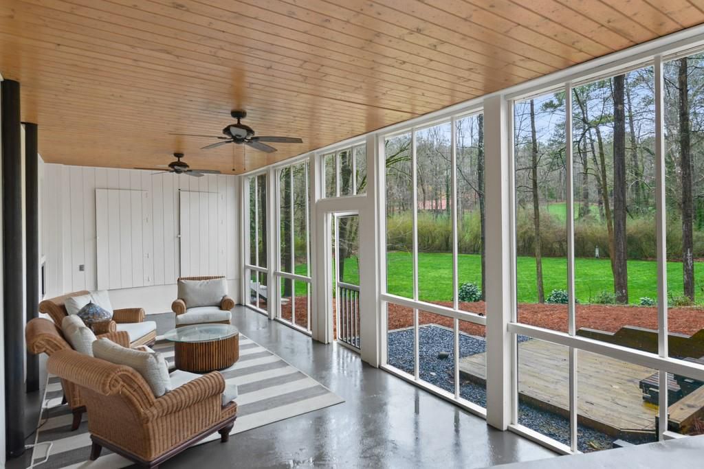 A screened-in porch area overlook a very green backyard. 
