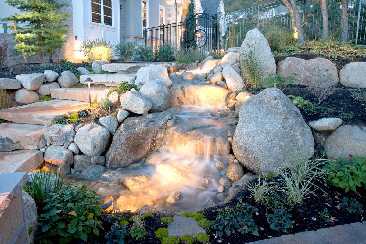 A lit up water feature filled with rocks. 