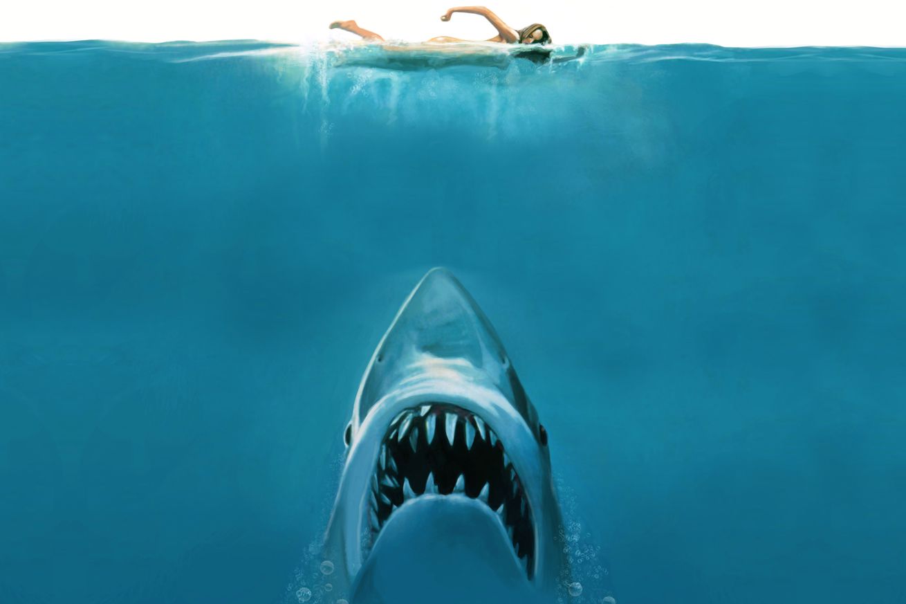 A still from a Jaws movie poster featuring a shark sneaking up on a swimmer.