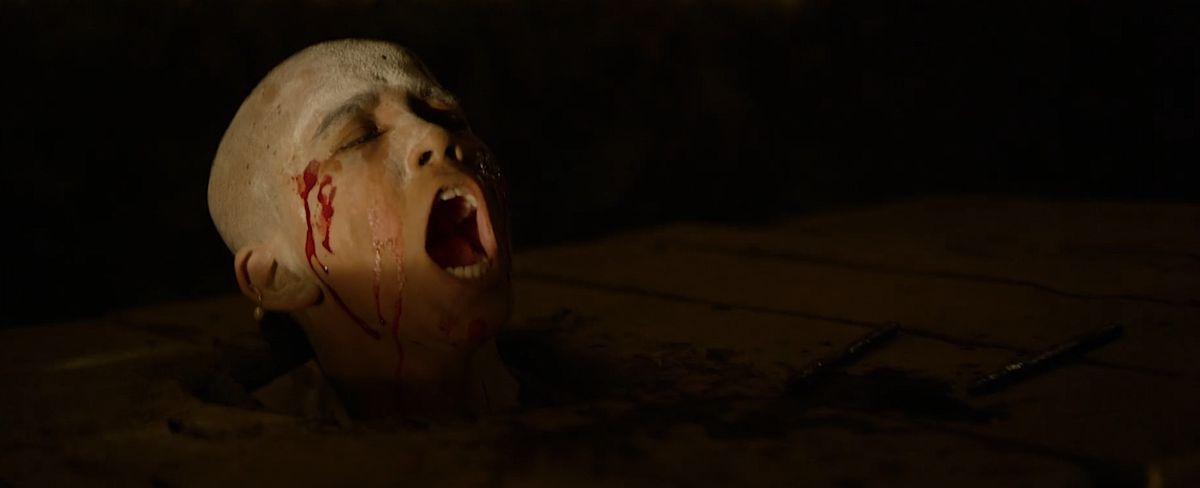 A child with a shaved head, covered in flour and drops of blood, closes his eyes and screams in the Indian horror film Tumbbad