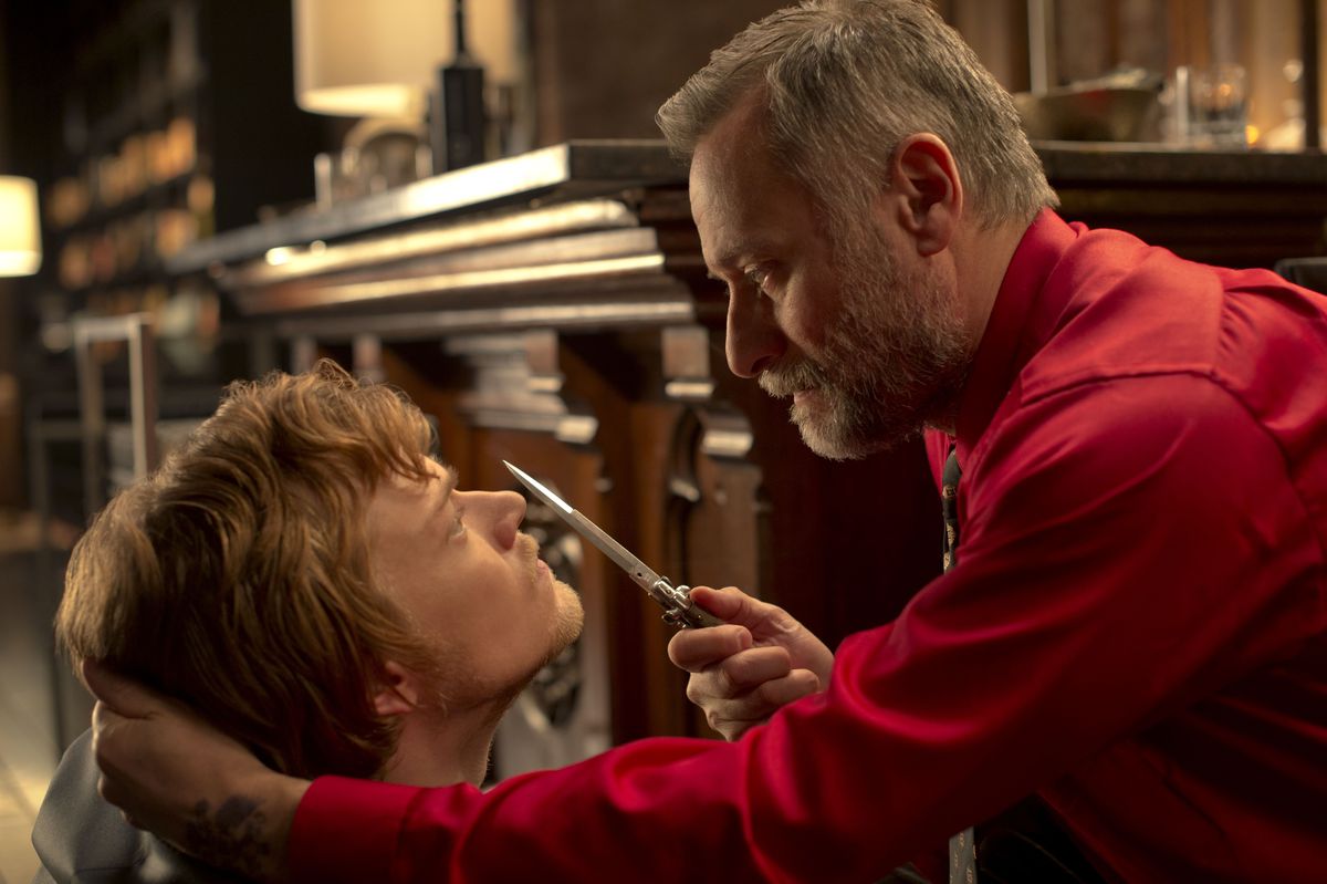 Viggo holds a knife to his son Iosef’s face in John Wick