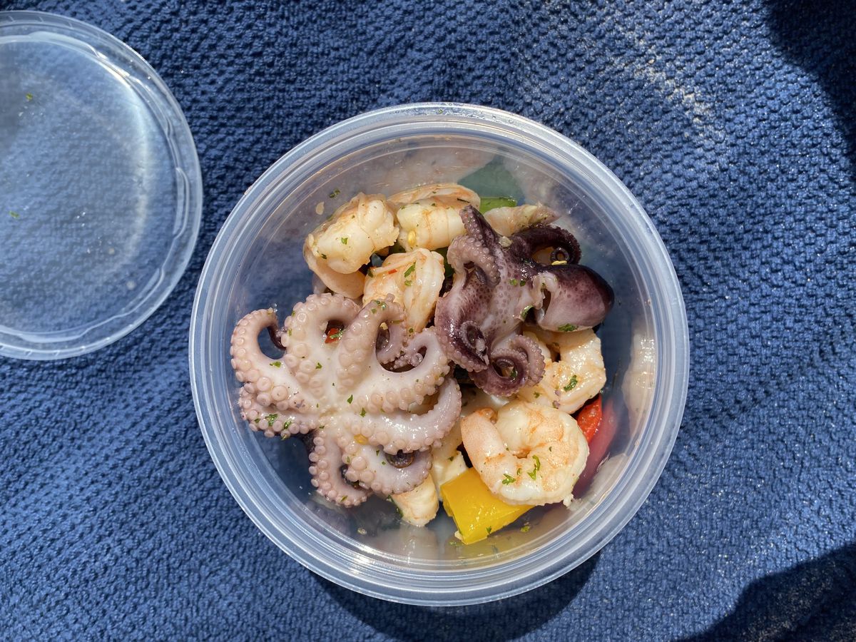 An overhead photograph of a plastic container filled with mini octopi and other seafood