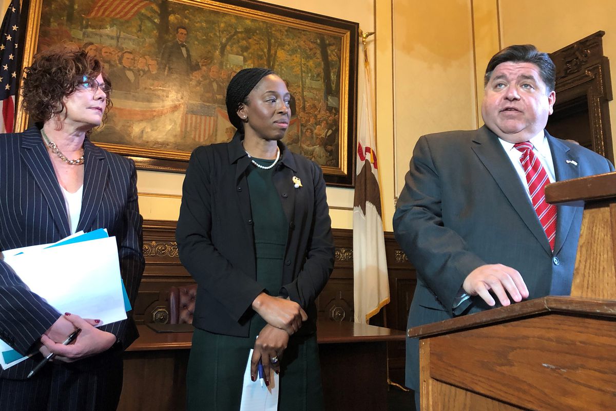 Alicia Tate-Nadeau (left), the director of the Illinois Emergency Management Agency, and Dr. Ngozi Ezike, Illinois’ public health director, stand by as Gov. J.B. Pritzker discusses the state’s response to COVID-19 at the state Capitol.