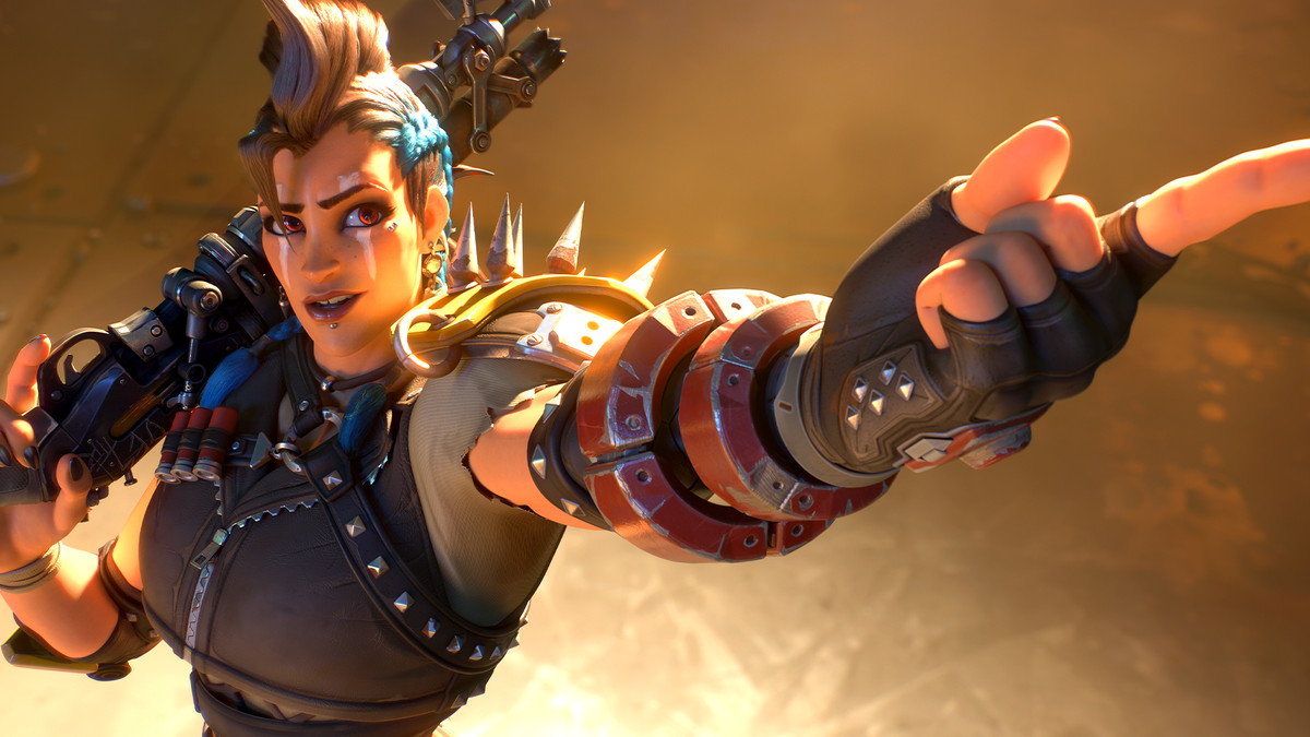 Image of new Overwatch 2 hero Junker Queen from the waist up wearing studded armor with a mohawk pointing at the camera