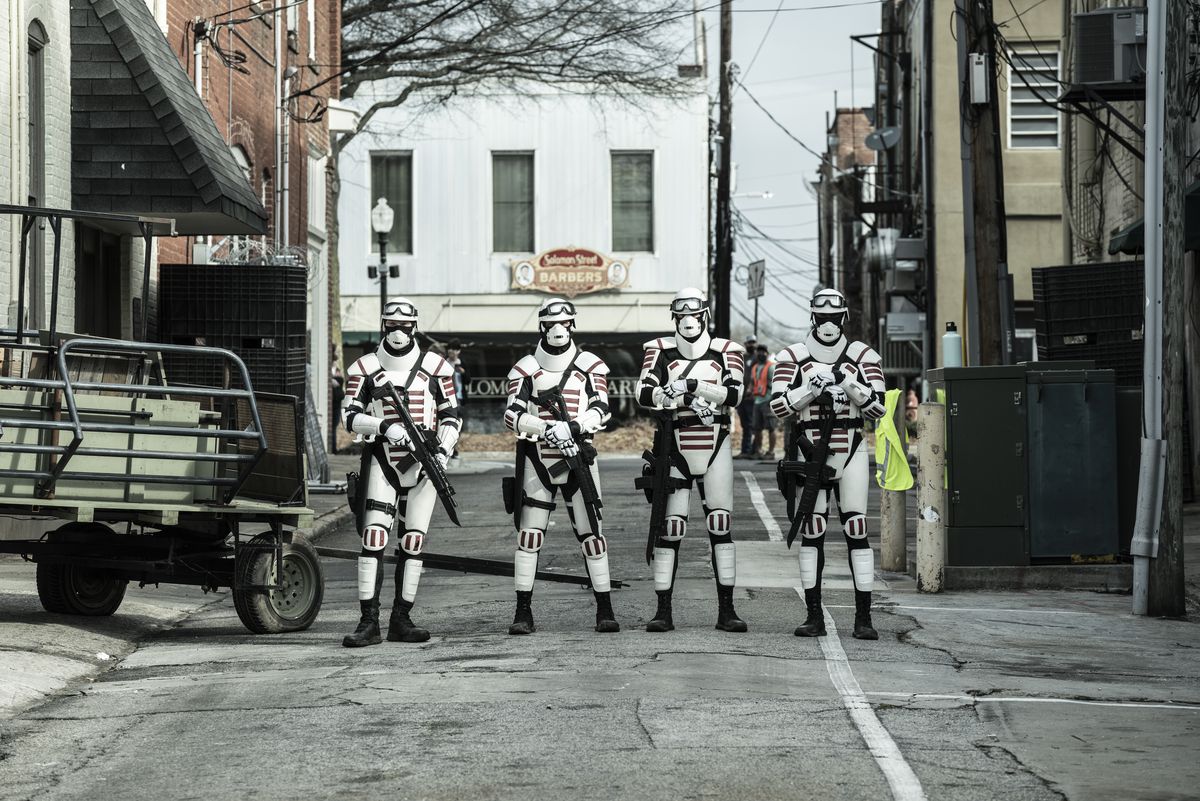 Four people dressed almost like Stormtroopers on an empty street with guns