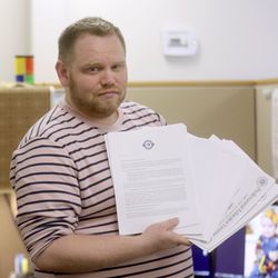 Jordan King, communications director at the American International School of Utah, holds a stack of papers the school submitted to the State School Board to appeal its decision AISU must refund $514,000 in state and federal education funding, at the school in Murray on Friday, May 3, 2019.