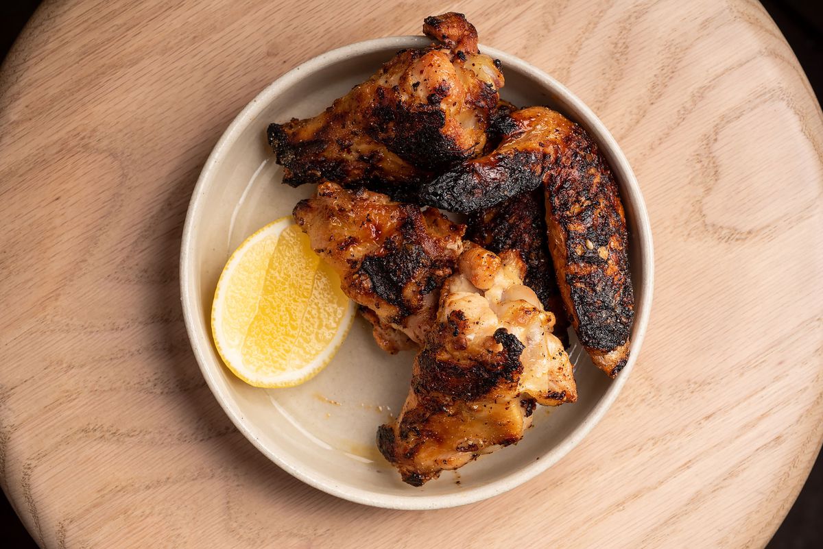 Crispy grilled chicken wings with a wedge of lemon.