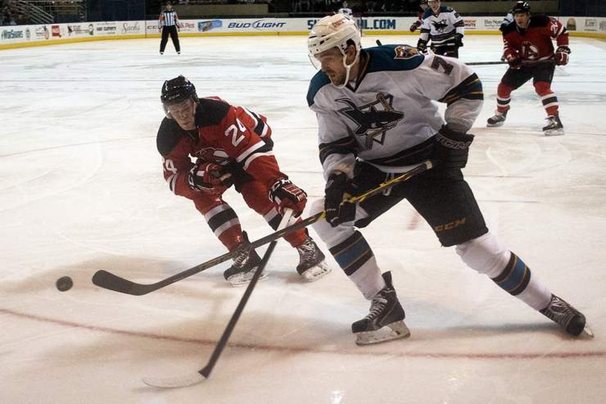 Worcester Sharks forward Eriah Hayes flips the puck over the outstretched hockey stick of Albany Devils defenseman Reece Scarlett (Rick Cinclair, Telegram.com).