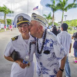 In this Monday, Dec. 5, 2016 photo, about 30 Pearl Harbor Survivors with the "Greatest Generation" vets meet and greet with visitors at the Pearl Harbor Visitor Center in Honolulu. Lt. Dawn Stankus, left, was there to help escort the Pearl Harbor survivors and Edward W. Stone, right, suddenly gave her a kiss and said I hope you don't mind. Which Stankus said "it was an honor to be kissed by you." On Wednesday, Dec. 7, thousands of servicemen and women and members of the public are expected to attend the 75th anniversary ceremony of the attack on Pearl Harbor that left more than 2,300 service people dead.  