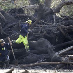 Emergency crew members work on storm damage in Montecito, Calif., Thursday, Jan. 11, 2018. Rescue workers slogged through knee-deep mud and used long poles to probe for bodies Thursday as the search dragged on for victims of the mudslides that slammed this wealthy coastal town. (AP Photo/Marcio Jose Sanchez)