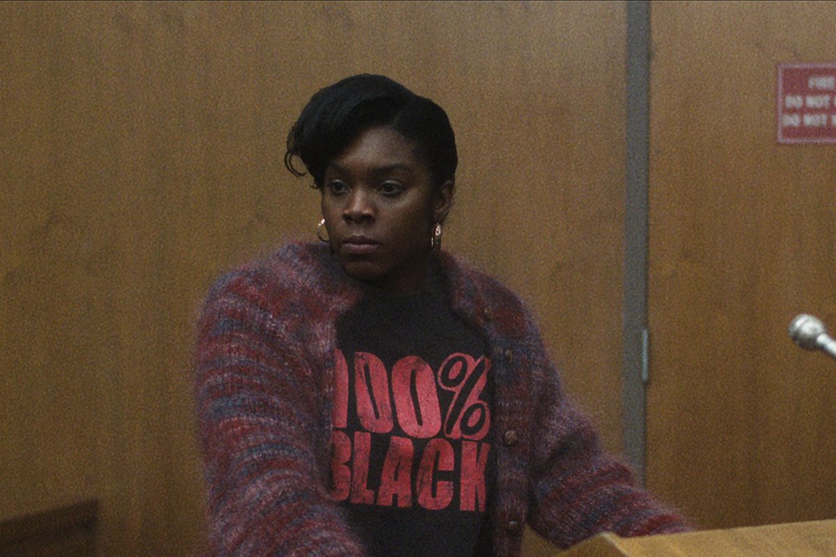 DaShawn Barnes as Rita Isbell stands at a podium in a courtroom, glaring at an off-screen Jeffrey Dahmer. She wears a T-shirt that reads “100% Black.”