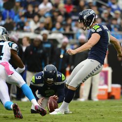 Seattle Seahawks kicker Steven Hauschka (4) kicks a field goal as punter Jon Ryan (9) holds and Carolina Panthers cornerback Josh Norman (24) defends during the first half at Bank of America Stadium.