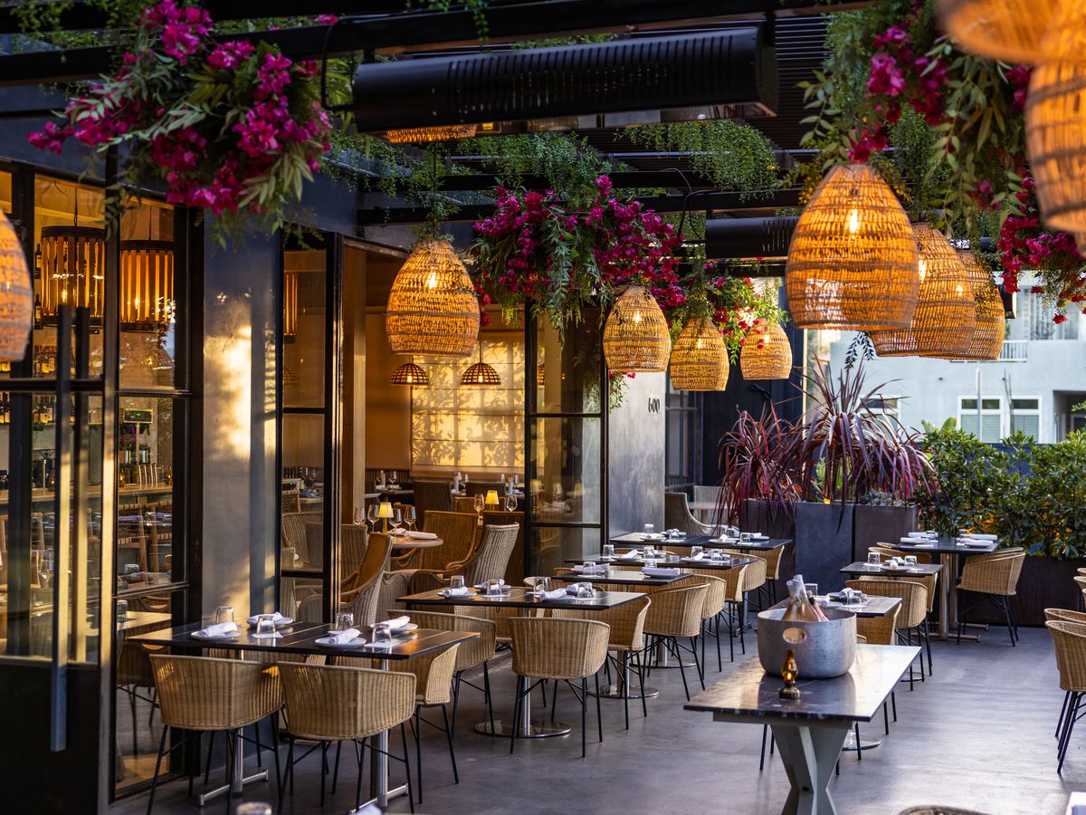 An outdoor dining area with hanging lamps and plants at Paloma restaurant in Venice, California.