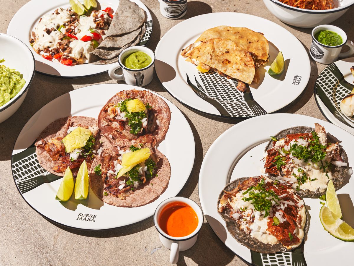 An assortment of tortilla dishes, including tacos and gringas, topped with meats and cheeses.