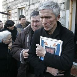 David Kumaritashvili, front, father of Nodar Kumaritashvili, the Georgian luger killed in a practice run at the Olympics, holds a photo of his son at his funeral Saturday in Bakuriani, Georgia. Thousands of Georgians paid their last respects to the young luger whose death cast a pall over the opening of the 2010 Winter Olympics and sent his nation into mourning.