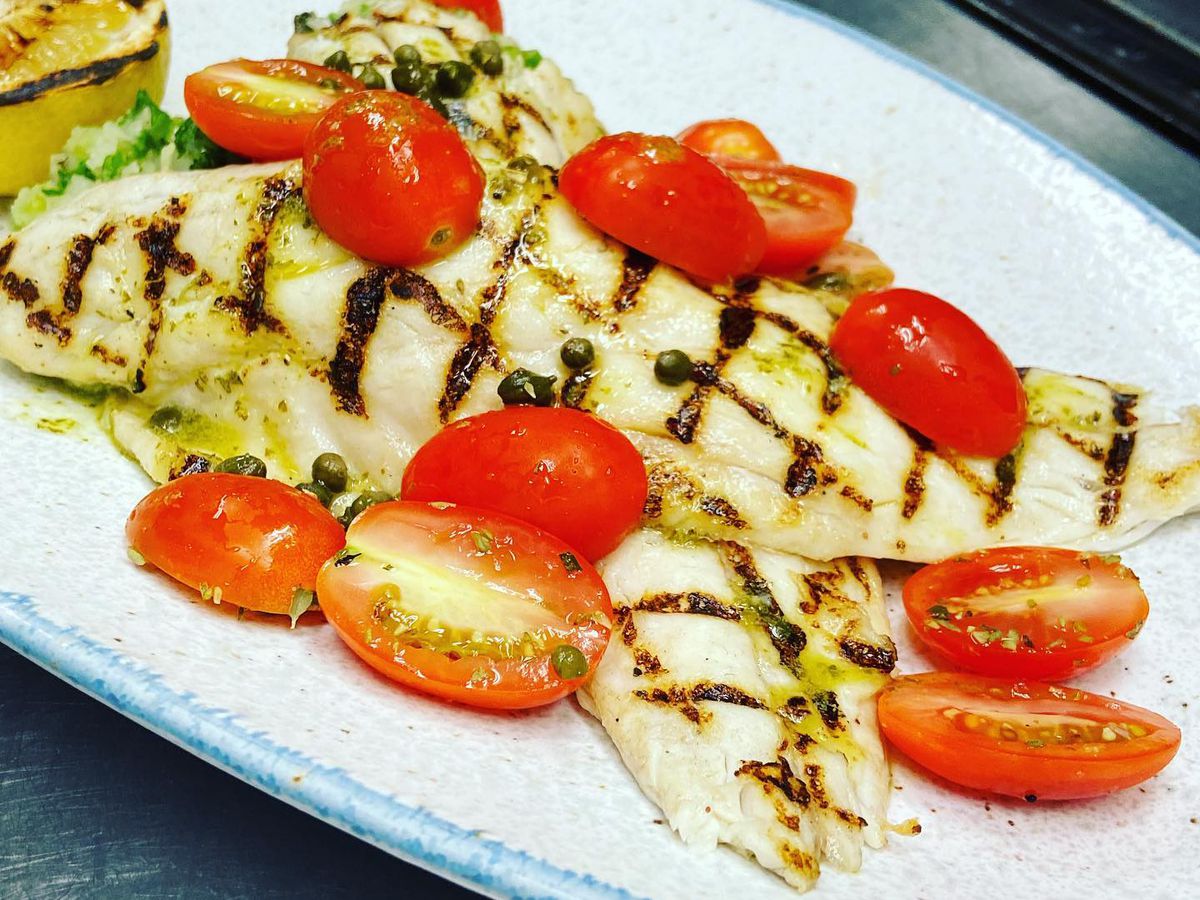 Grilled fish filets covered with grape tomatoes.
