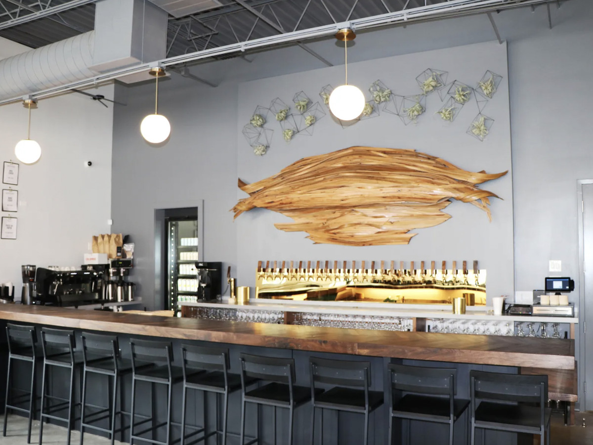 A bar space with gold colored tappers and a large wood wall sculpture.